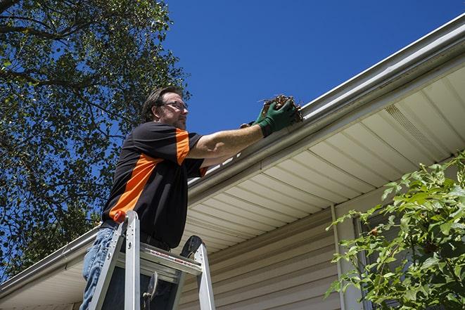 a person replacing a worn-out gutter on a building in Aguanga CA